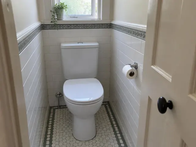Clean white toilet in a tiled small bathroom with a window and door frame in Naremburn